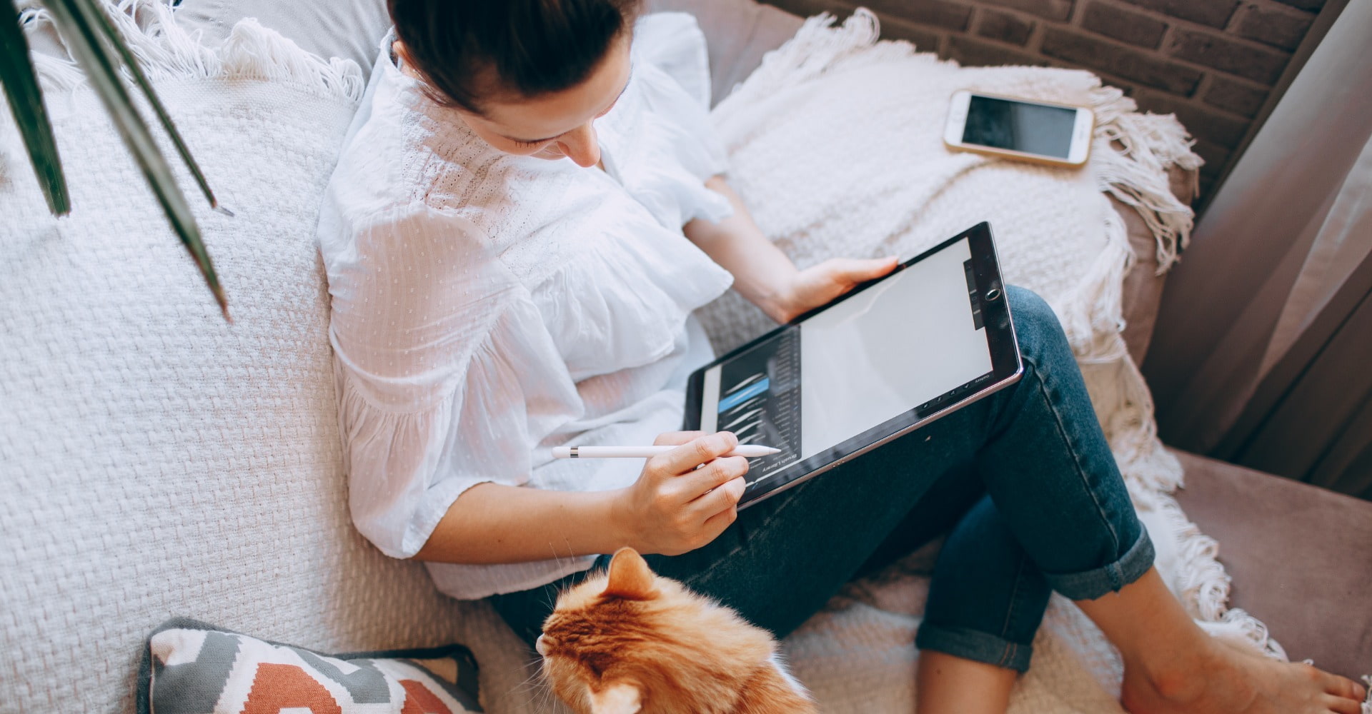 Woman sat down with a cat using her iPad