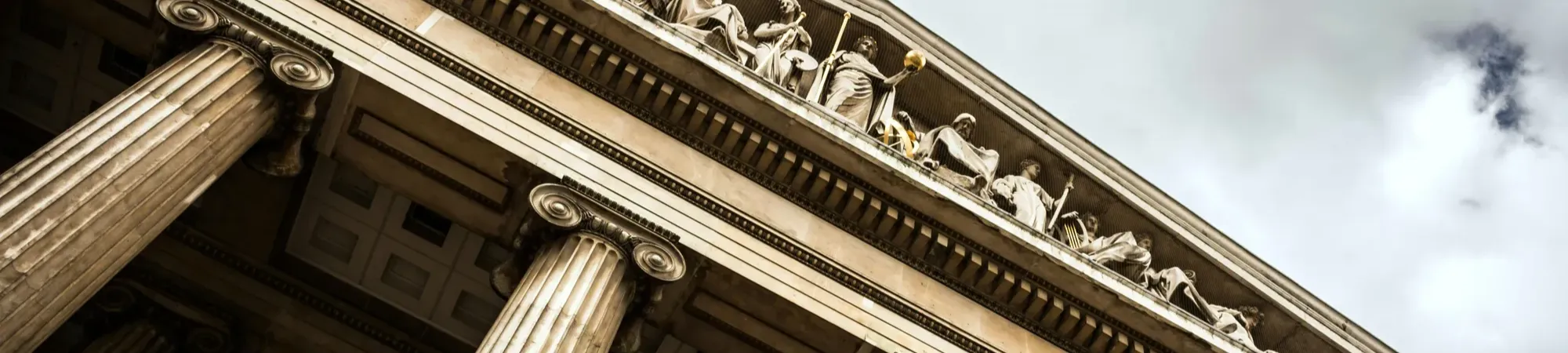 British Museum facade with stone pillars and statue details on the roof peak