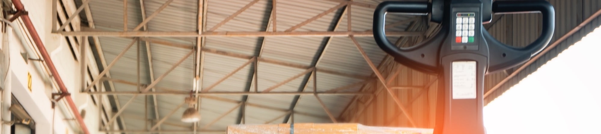 Warehouse operator actively using a powered pallet truck among stacked goods – dynamic and relevant to daily operations