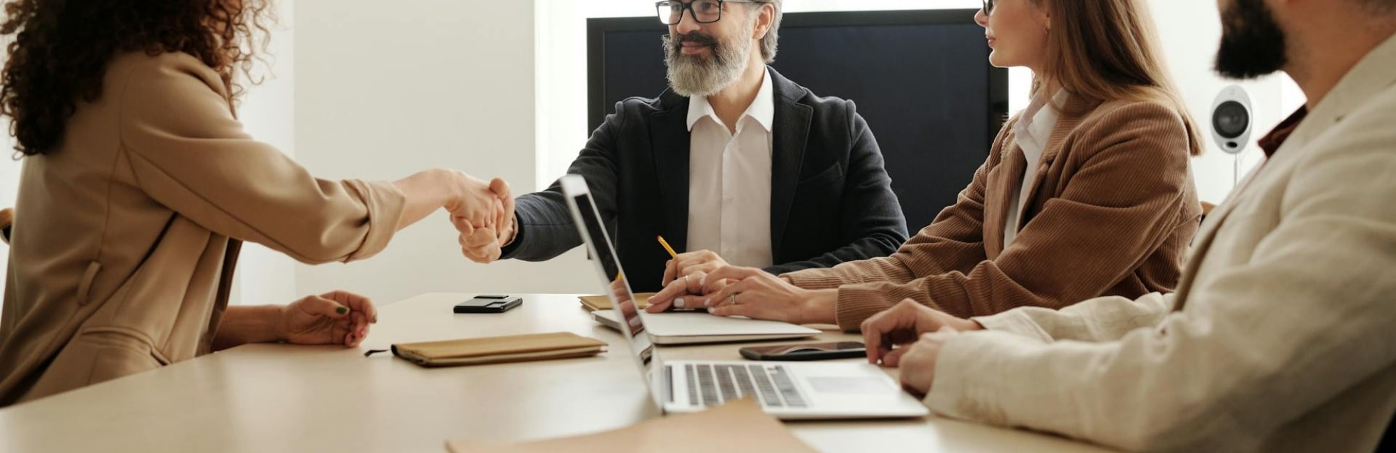 A businesswoman shakes hands with a panel during her second job interview, showcasing professionalism and confidence.