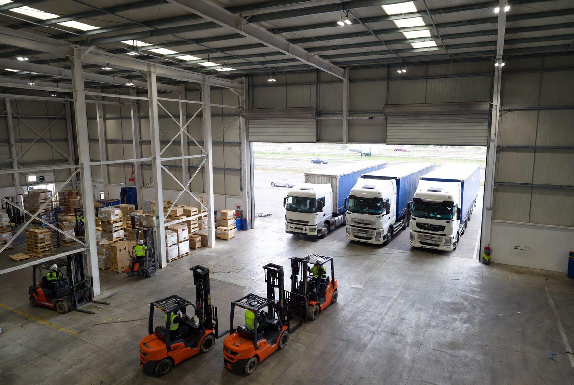 Modern logistics warehouse in Milton Keynes with HGV trucks and forklift operators – representing warehouse jobs and driving jobs opportunities through MAK Jobs recruitment agency
