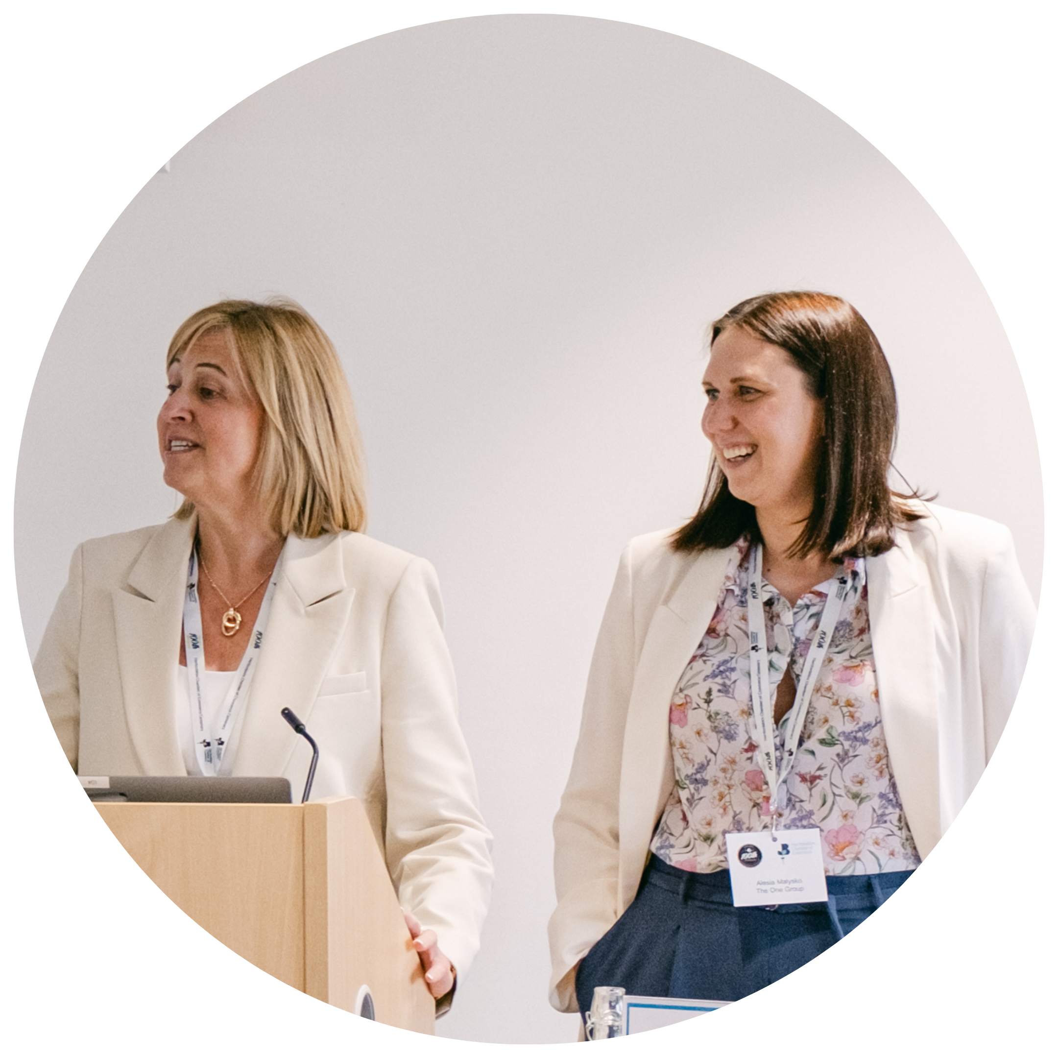 People smiling at a networking event stood at the front of the room behind a podium.