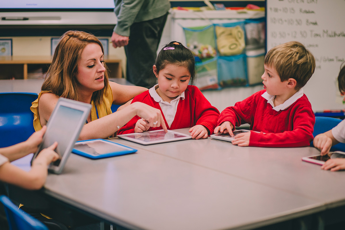 Young Children At Desk With Teacher