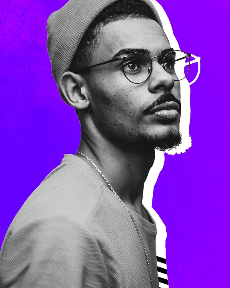 Man with glasses standing against purple background