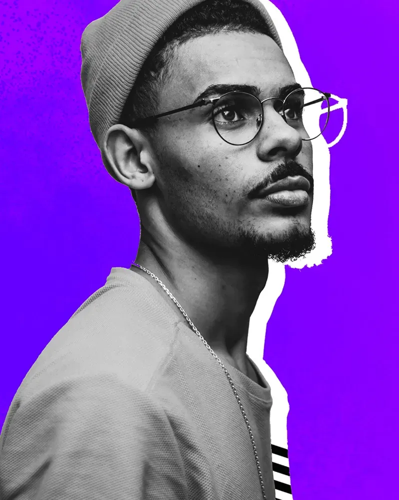 Man with glasses standing against purple background