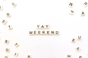 Scrabble letters displaying the word "weekend" set against a classic game board background.