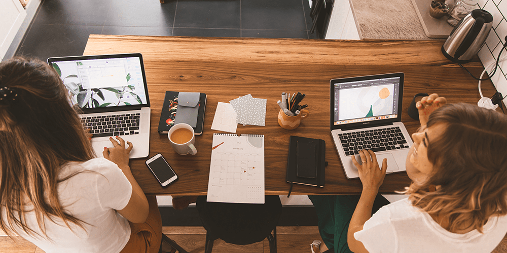 two women working on laptops with coffee; international women's day