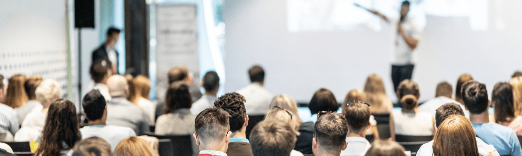 View of a man presenting to employees from the point of view of an audience member