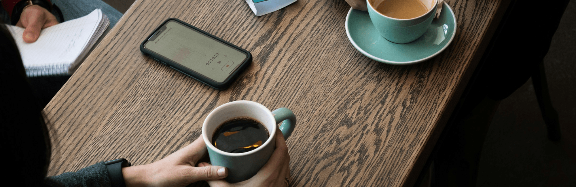 Two people engaged in a job interview, sitting at a table with coffee cups in front of them.
