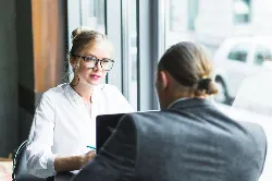 Women facing another person, in a cafe they are dressed professionaly