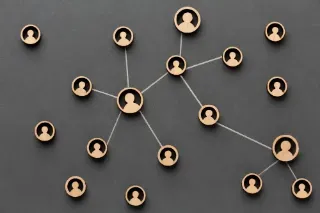 Individuals linked by a network of wooden figures, representing the concept of building connections and teamwork.