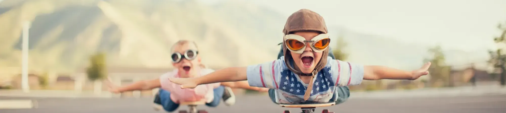 kinderen die doen alsof ze vliegen op een skateboard, met een piloten muts en bril