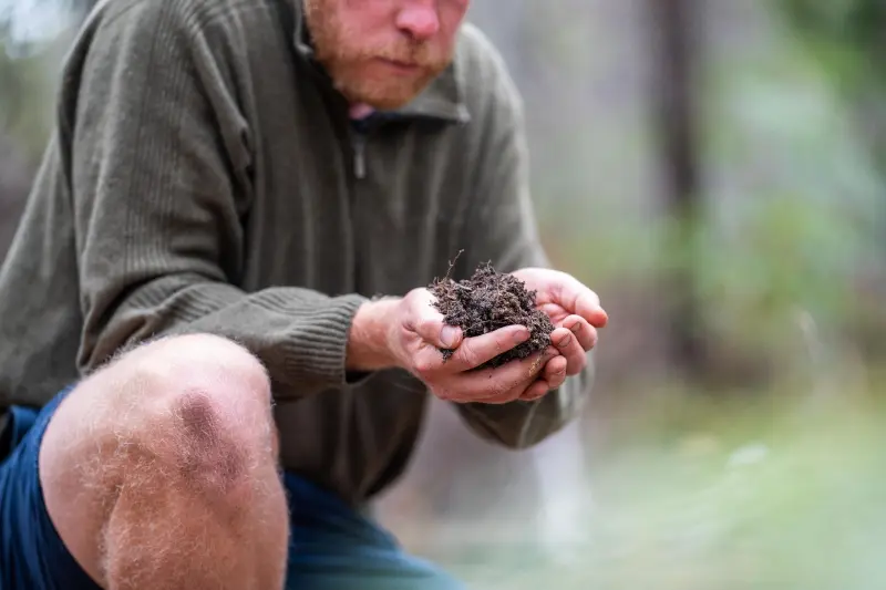 A farmer examining the soil on their farm