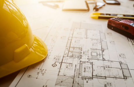 Hardhat on table with tech drawings