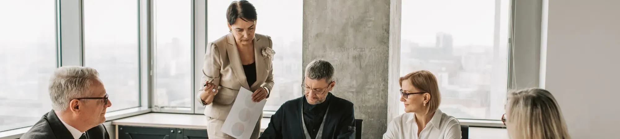 A group of business professionals seated around a conference table engaged in discussion.
