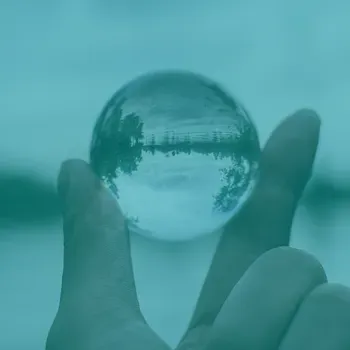 A hand holding a clear glass ball 