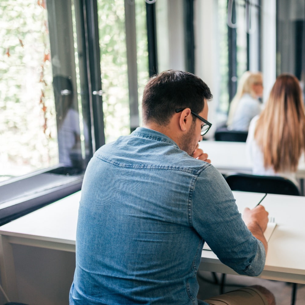 man in shirt sitting at desk holding pencil preparing cover letter