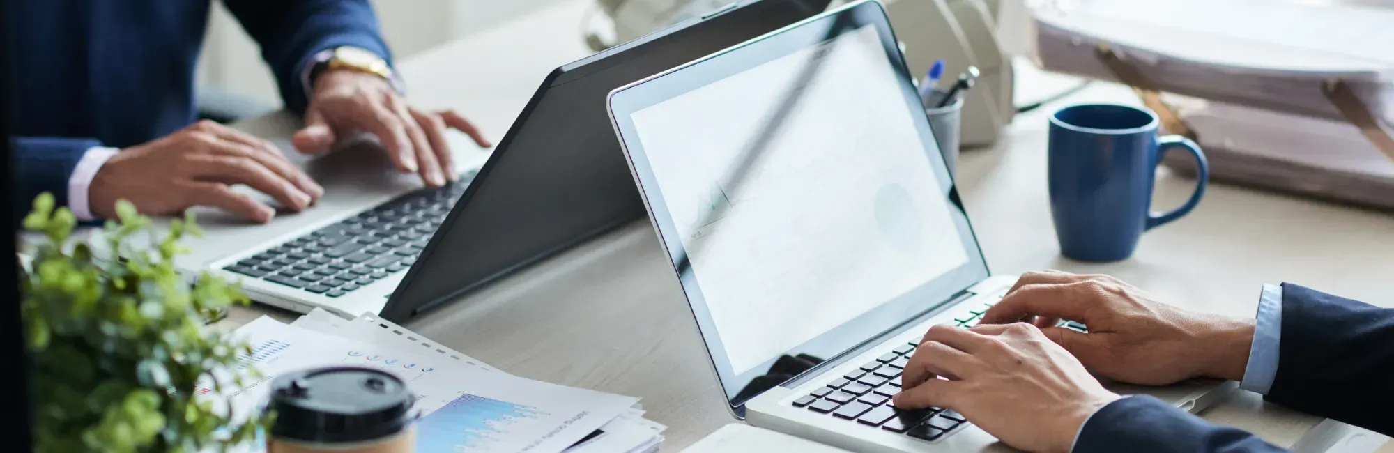 A work desk scene featuring two people engaged with their laptops, collaborating on a project.