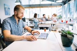 Man working at desk with group working in background