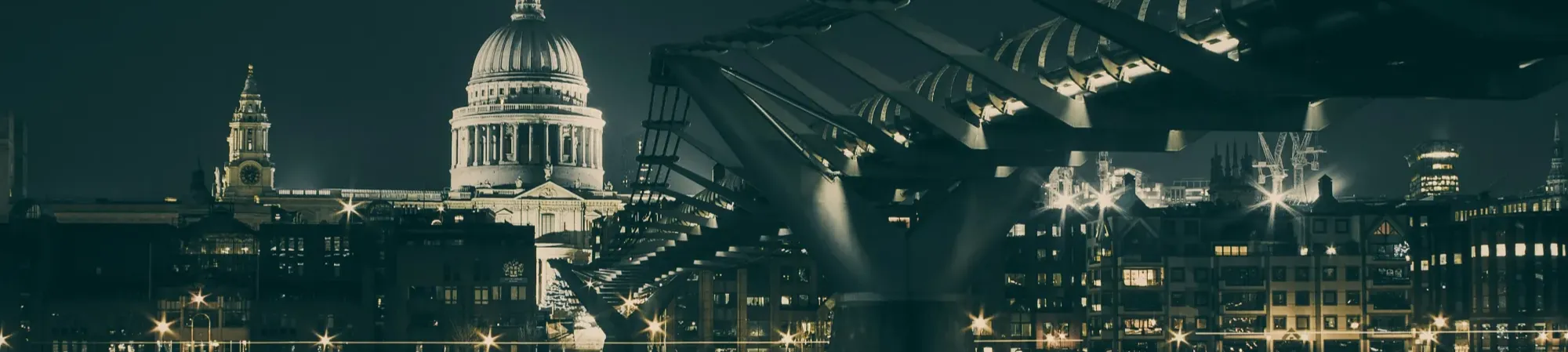 Millennium Bridge London with St Pauls in the background at night.