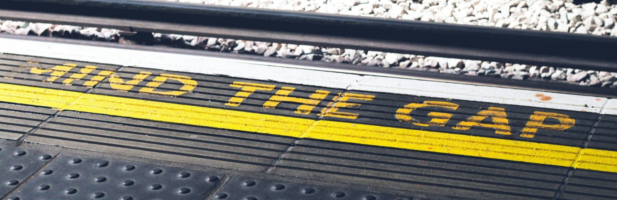 A train parked on a platform next to a safety sign reading "find the gap" to alert passengers about the platform edge.