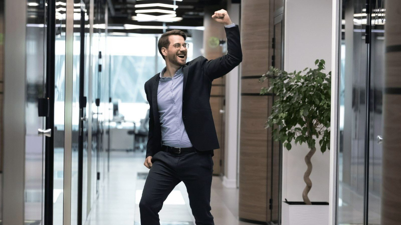 A man in corporate clothes raising his hand up in victory