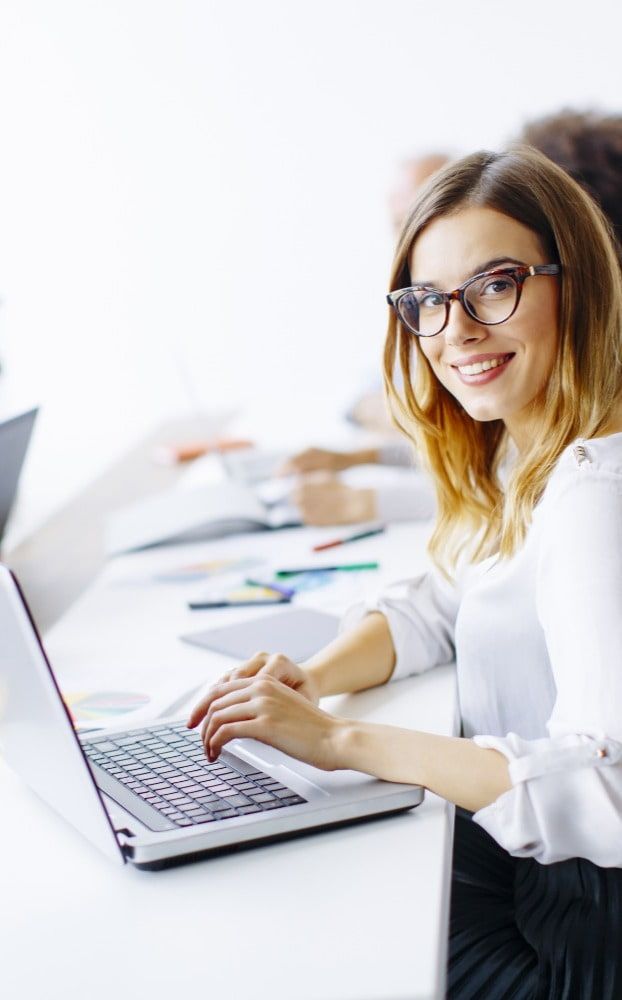 Woman smiling at camera while working on laptop