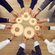 Image of many hands holding cogs working together