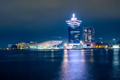 een stad in de nacht. De foto is gemaakt vanaf het water, gebouwen geven licht. 