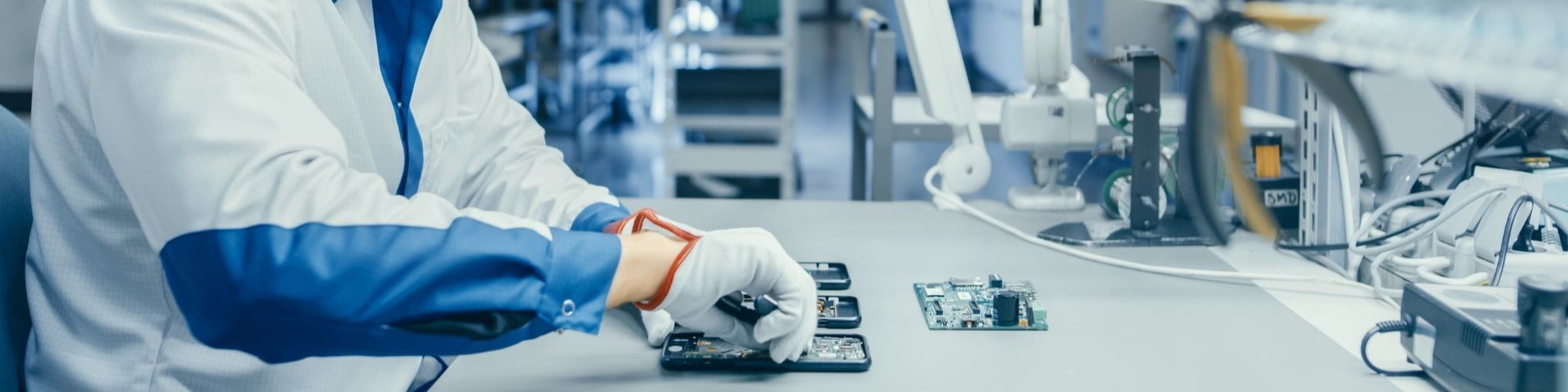 engineering technical specialist using plier to assemble Printed Circuit Board for Smartphone. Electronics Factory Workers in a High Tech Factory Facility