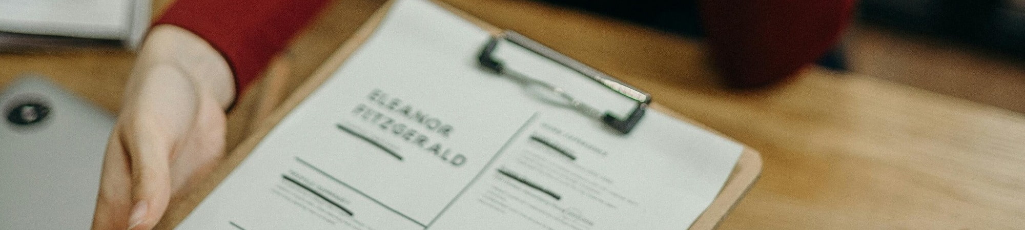 A woman holding a clipboard with a list, reviewing items related to her finance and accountancy candidate CV.