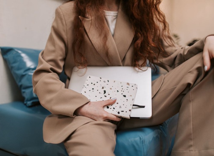 woman in beige suit sitting on sofa holding laptop