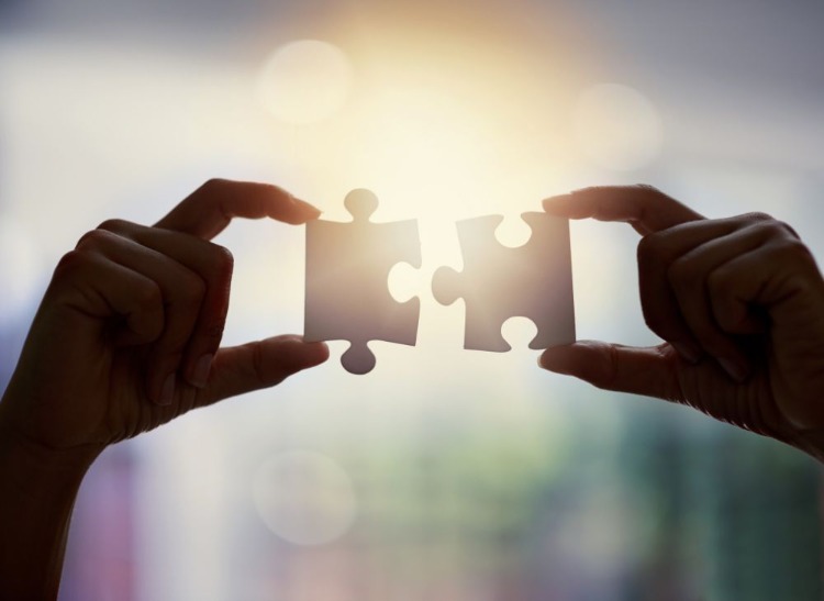 woman holding two puzzle pieces up