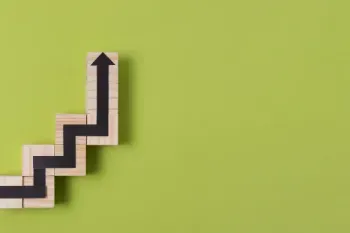 A wooden block featuring an upward arrow against a green backdrop, representing advancement and progression.