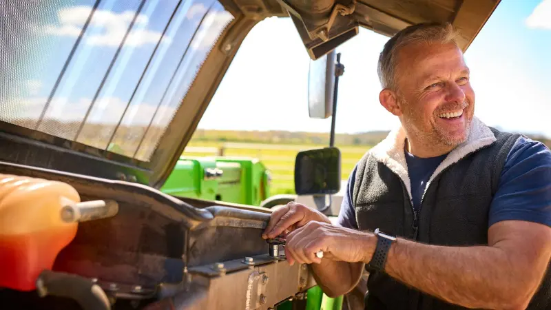 Smiling farmer making repairs on farm machinery equipment