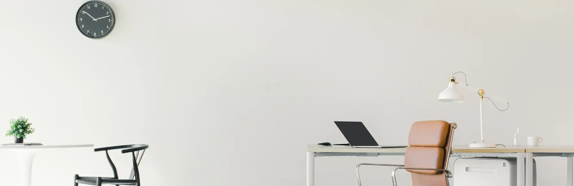 A bright white office featuring a desk, a chair, and a wall clock, creating a clean and organized workspace.