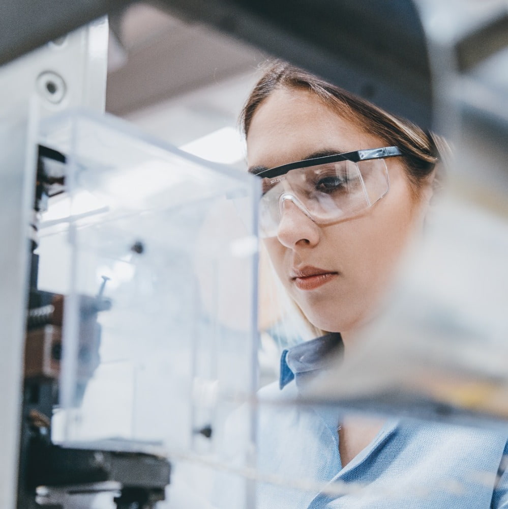 Female agency worker working with machine parts putting, checking and testing industrial equipments cables in large Electric electronics wire and cable manufacturing plant factory warehouse