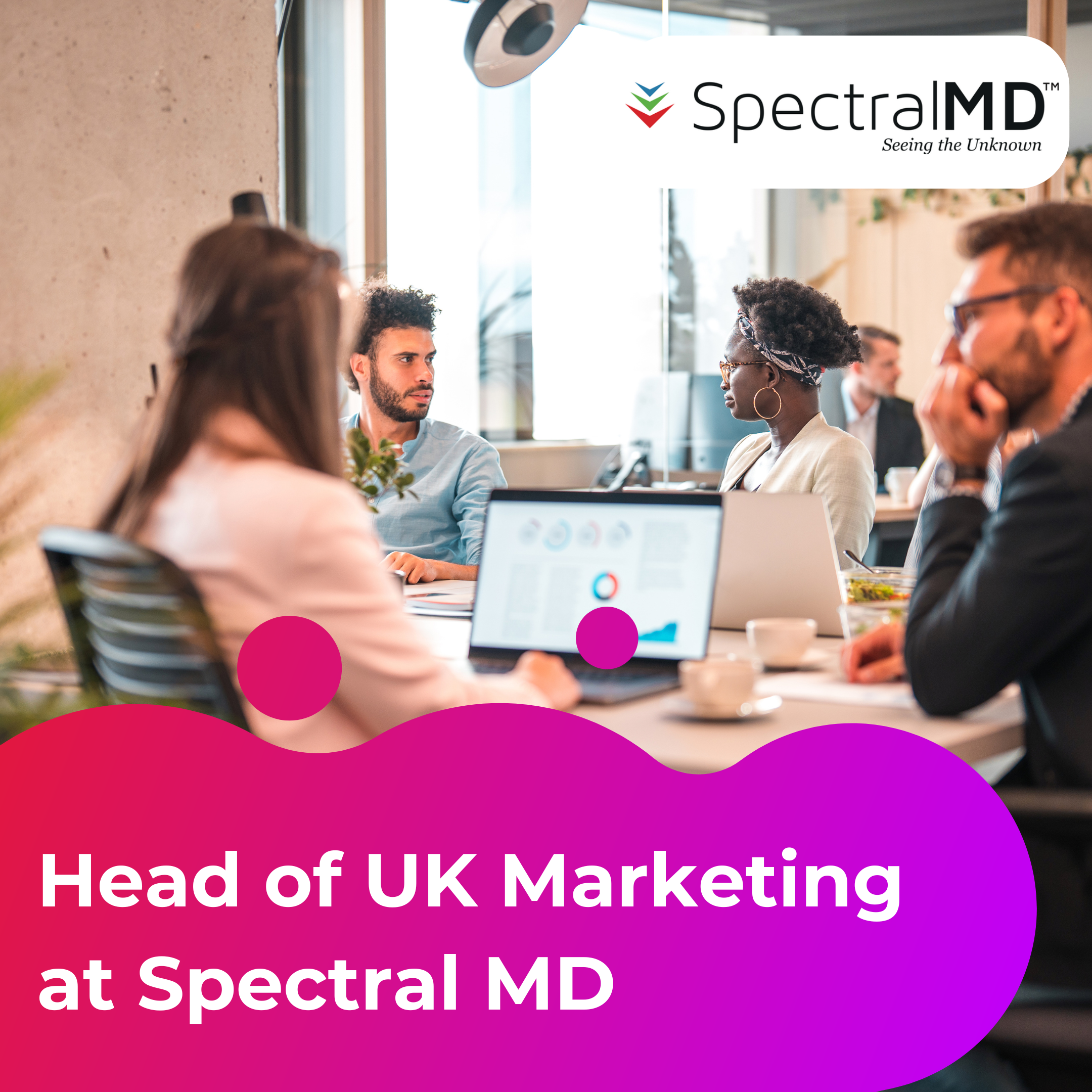 Head of UK Marketing at Spectral MD Case Study. The image shows four people sat in an office meeting room around a table. They are having a discussion and looking at a laptop screen.