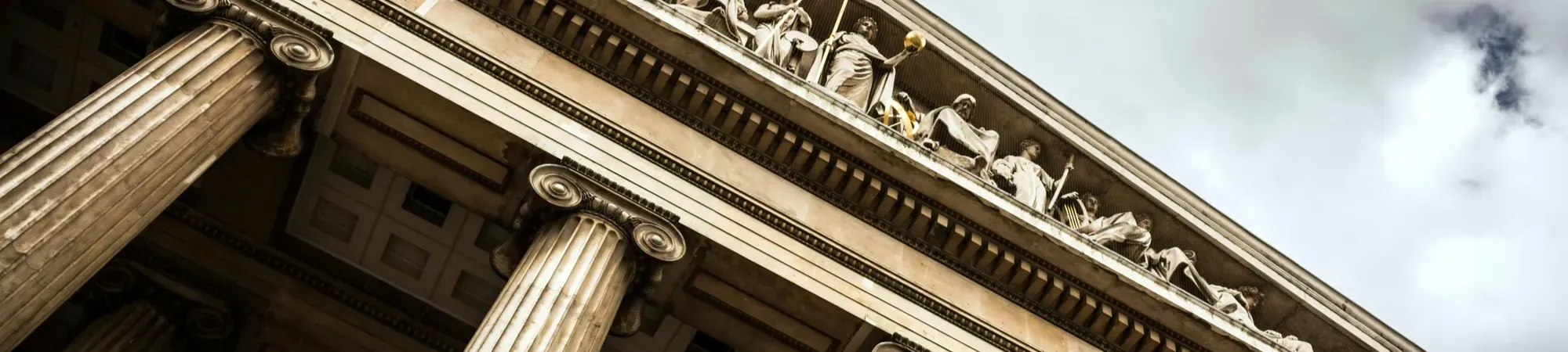 British Museum facade with stone pillars and statue details on the roof peak