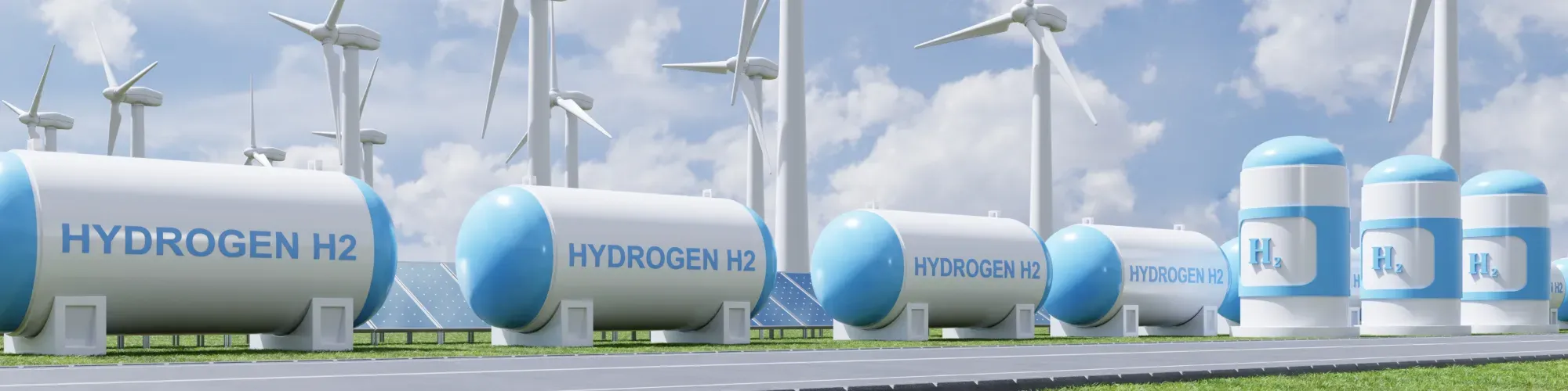A group of hydrogen tanks with wind turbines in the background