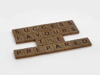 A collection of Scrabble tiles arranged to read "success favours the prepared," highlighting strategic planning.