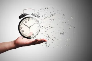 An individual grips an alarm clock from which water flows, representing the concept of time and its long-term implications.