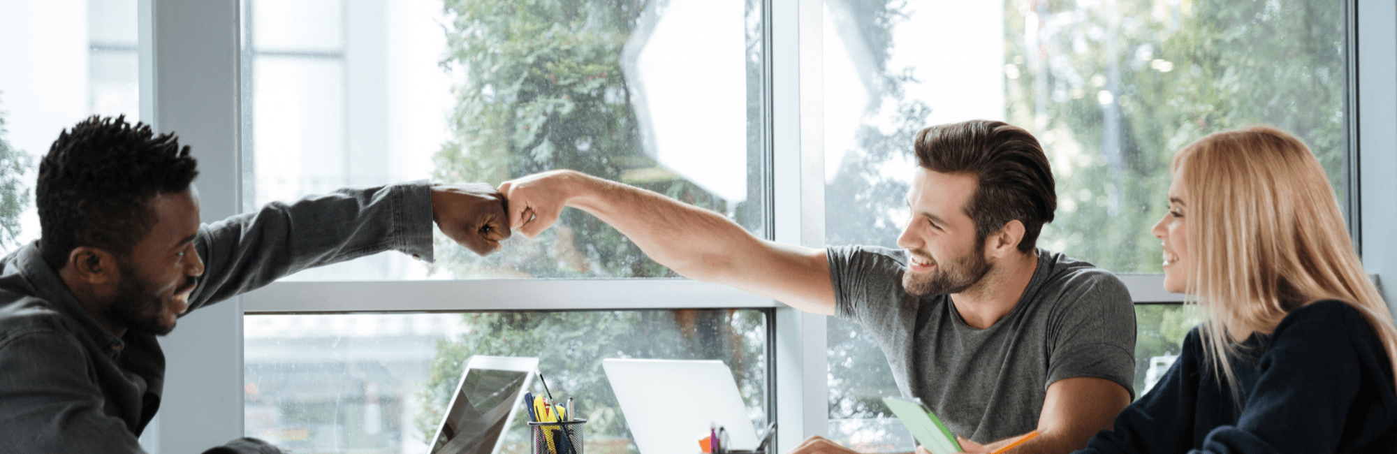 Three people around a table, one individual pointing at another, suggesting an interactive dialogue.