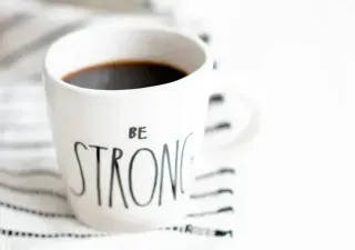 Coffee cup displaying "be strong," conveying a message of encouragement and inner strength.