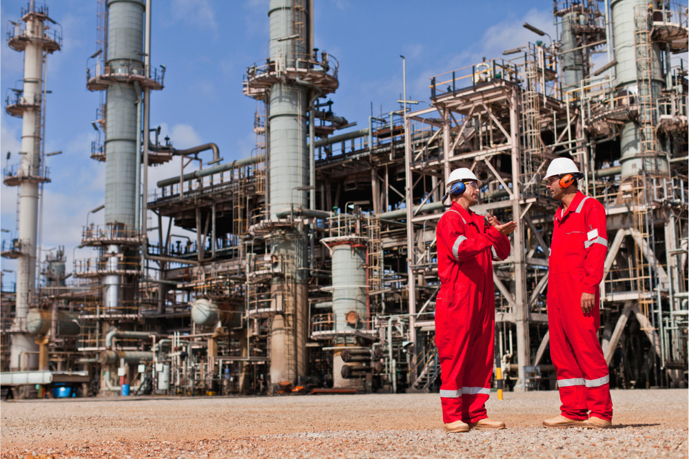 2 men standing outside an oil refinery during their oil and gas engineering jobs