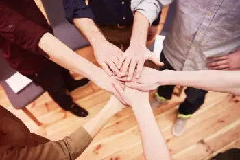 A team of people collaboratively putting their hands together, illustrating the spirit of teamwork.