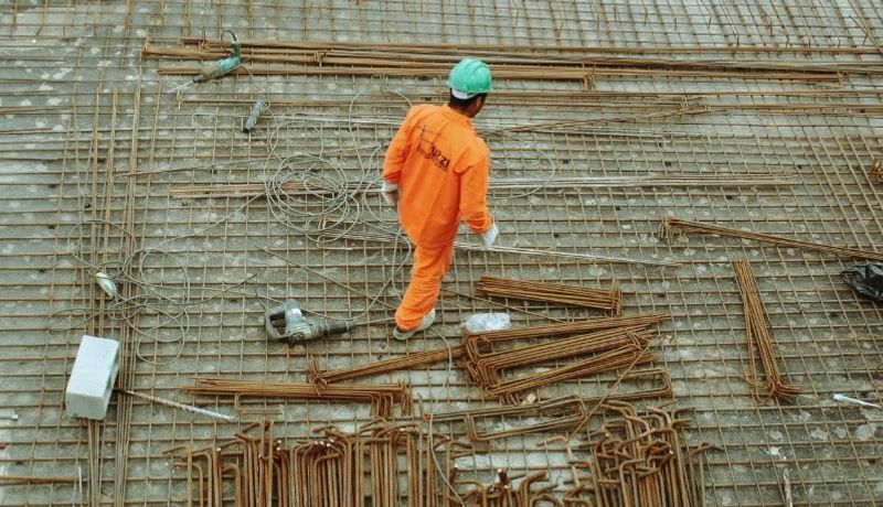 A construction worker in orange uniform walking on the construction site.