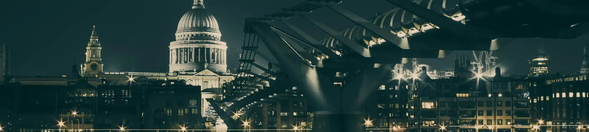 Millennium Bridge London with St Pauls in the background at night.