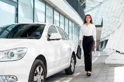 Woman walking by white car