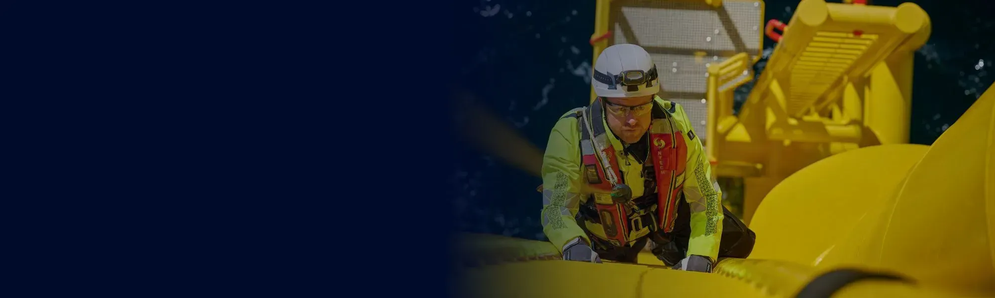 Worker in hard hat with arms folded in front of cargo container units.